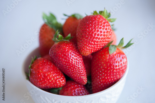 Strawberries in the ceramic bowl on the table. Natural day light.