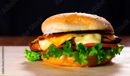 Fresh and Juicy Burger on a Wooden Table with Cheese Lettuce and Tomato