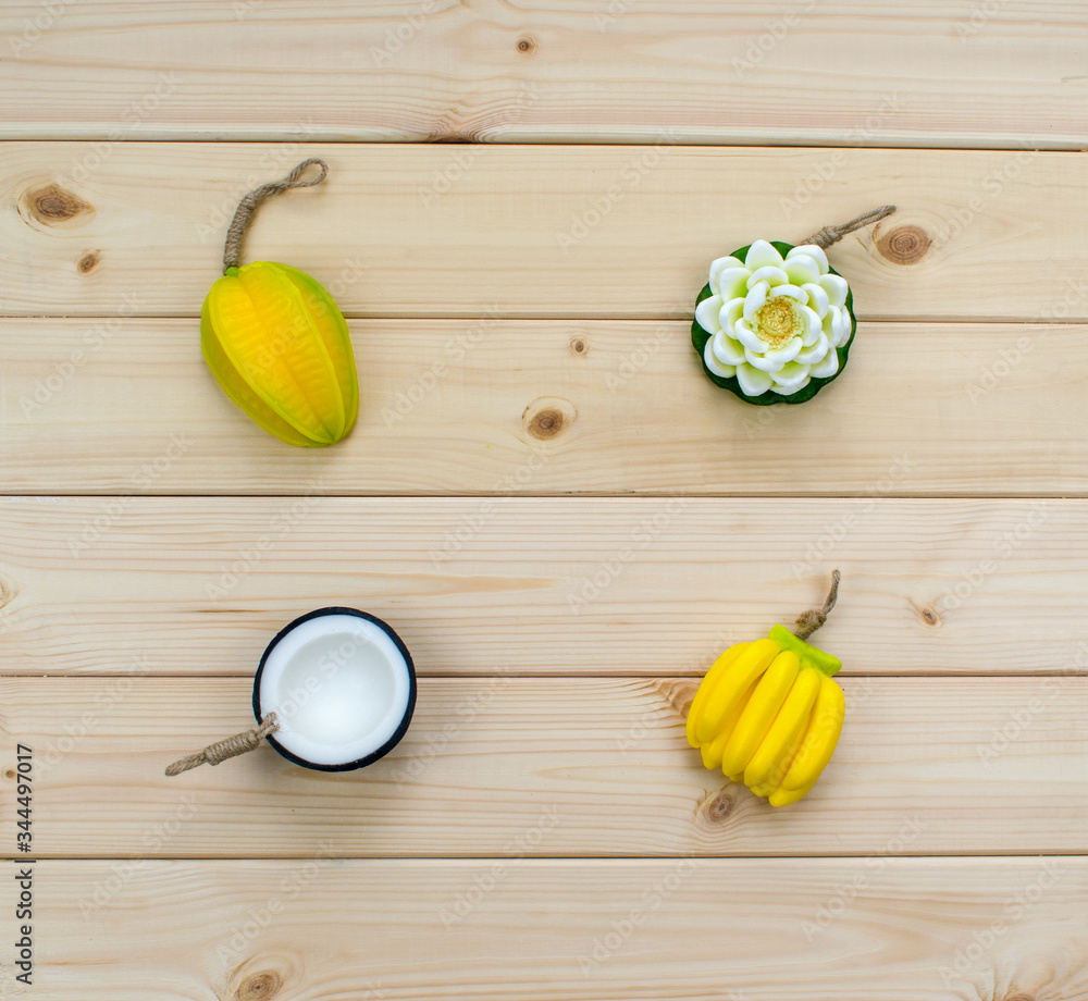 Hand made soap in the shape of tropic fruits mini bananas, carambola, flower and half of a coconut on wood background. Artificial fruits from Thailand. Hand made soap in the shape of tropic fruits mini bananas, carambola, flower and half of a coconut on wood background. Artificial fruits from Thailand.