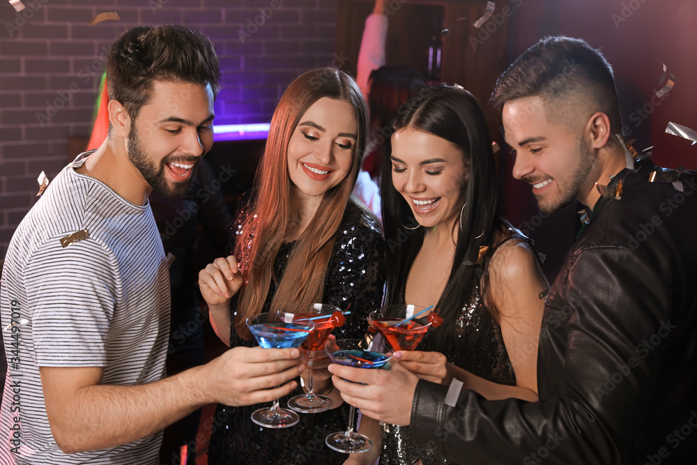 Happy young people with cocktails in night club