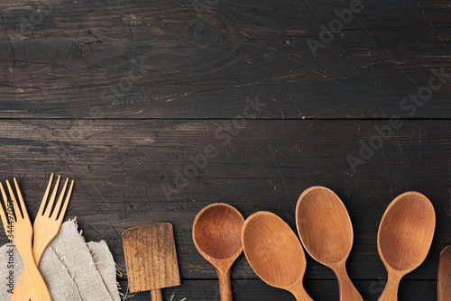 empty wooden spoons, forks and spatulas on a brown wooden background from boards