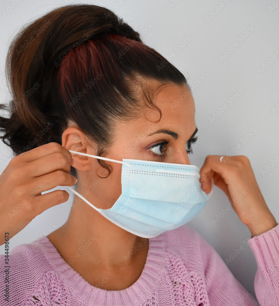 Young woman putting on a surgical mask during the quarentena period, coronavirus Young woman putting on a surgical mask during the quarentena period, coronavirus