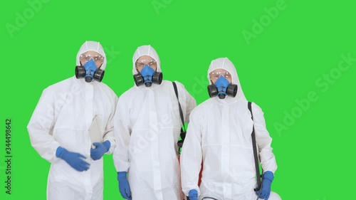 Three disinfectors walk in holding the disinfectant in their hands on a Green Screen, Chroma Key. photo