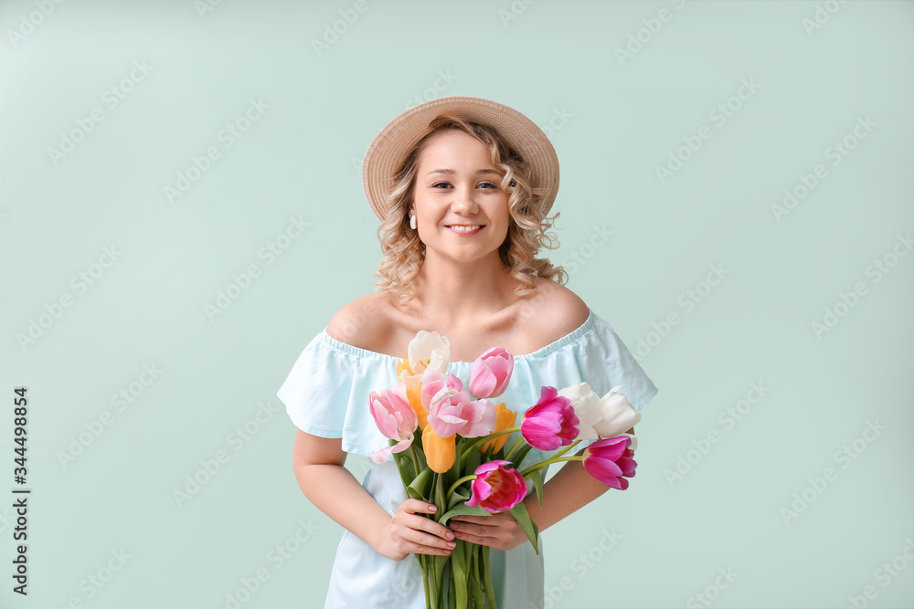 Beautiful young woman with bouquet of flowers on color background