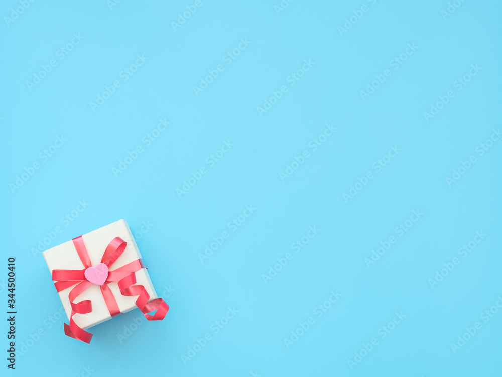 White giftbox with red ribbon and pink heart on blue background. Mother day, Valentine day, Wedding, Birthday concept. Greeting or invitation card. Flat lay style with copy space. White giftbox with red ribbon and pink heart on blue background. Mother day, Valentine day, Wedding, Birthday concept. Greeting or invitation card. Flat lay style with copy space.