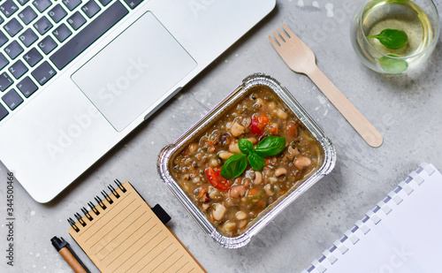 Food delivery. lunch box with a diet lunch or dinner on grey office table. Stewed beans with vegetables, takeaway lunch at the office. Top view. takeout healthy lunch. selective focus