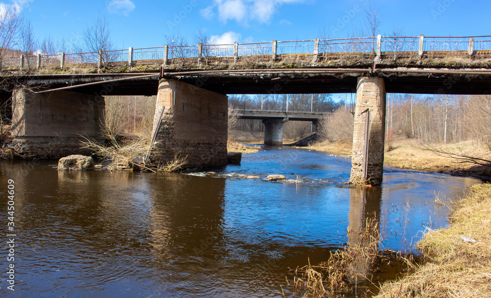 An old concrete bridge over a small river in early spring