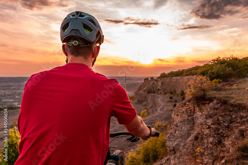 Back shot of mountain biker at sunset with modern bicycle helmet. © Yuri Hoyda