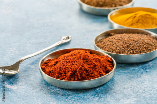 Ground spices in pots - paprika, nutmeg, tumeric and cumin - closeup with selective focus