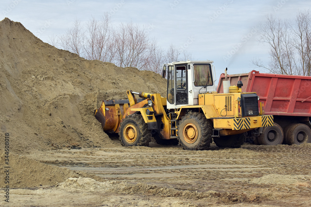 tractor picks up sand in a bucket 