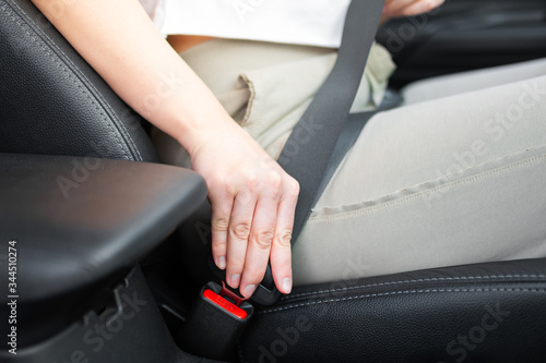 Safety driving concept. Woman hand fasten her seatbelt before start movement closeup.