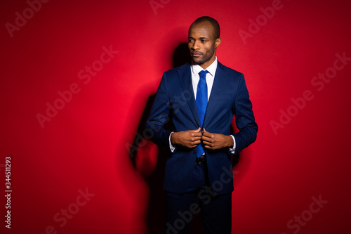 Photo of handsome attractive dark skin business guy look side buttoning blazer clothing for corporate meeting wear blue formalwear suit tuxedo isolated vivid burgundy background