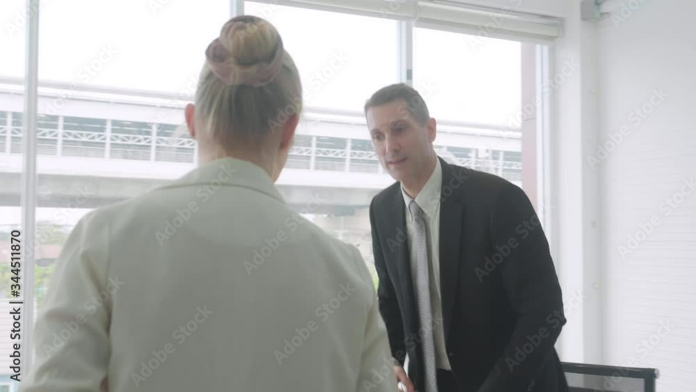 Businesswoman give financial profit report document with manager, businessman reading report with marketing or agreement and handshake, successful and partnership, business and communication concept. Businesswoman give financial profit report document with manager, businessman reading report with marketing or agreement and handshake, successful and partnership, business and communication concept.