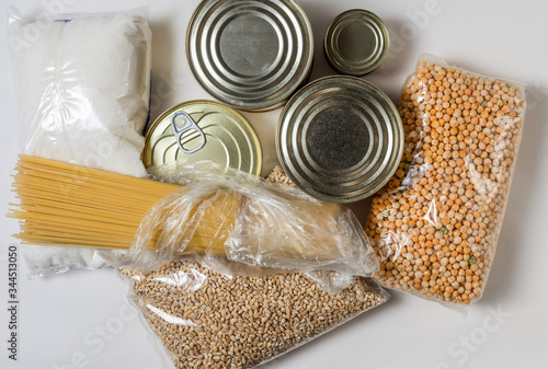 Long-term storage products. Canned meat and fish, spaghetti paste, sugar, dry peas and pearl barley in packs on a white background
