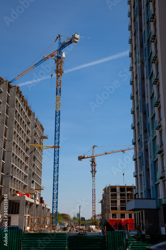 Cranes at the construction site of multi-unit high buildings. Construction of a molded concrete house. New buildings with a large number of apartments. New housing estates. Street.