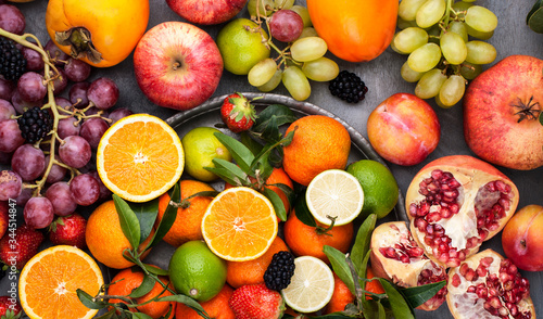 Assorted fruits. Different fruits on a gray background  the whole surface is covered with citrus fruits  pomegranates  apples  grapes  strawberries. Top view.