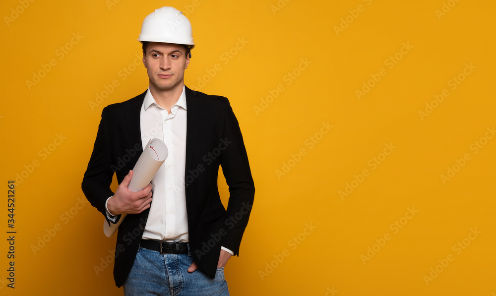 Engineer businessman. Close-up photo of a serious businessman in smart casual outfit and helmet, who is holding a blueprint in his right hand and looking aside. Engineer businessman. Close-up photo of a serious businessman in smart casual outfit and helmet, who is holding a blueprint in his right hand and looking aside.