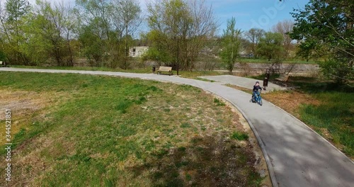 the boy was riding in the Park on a blue bike with side wheels