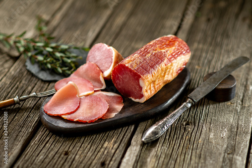 Smoked meat on wooden board with rosemary fork knife cuisine wooden texture