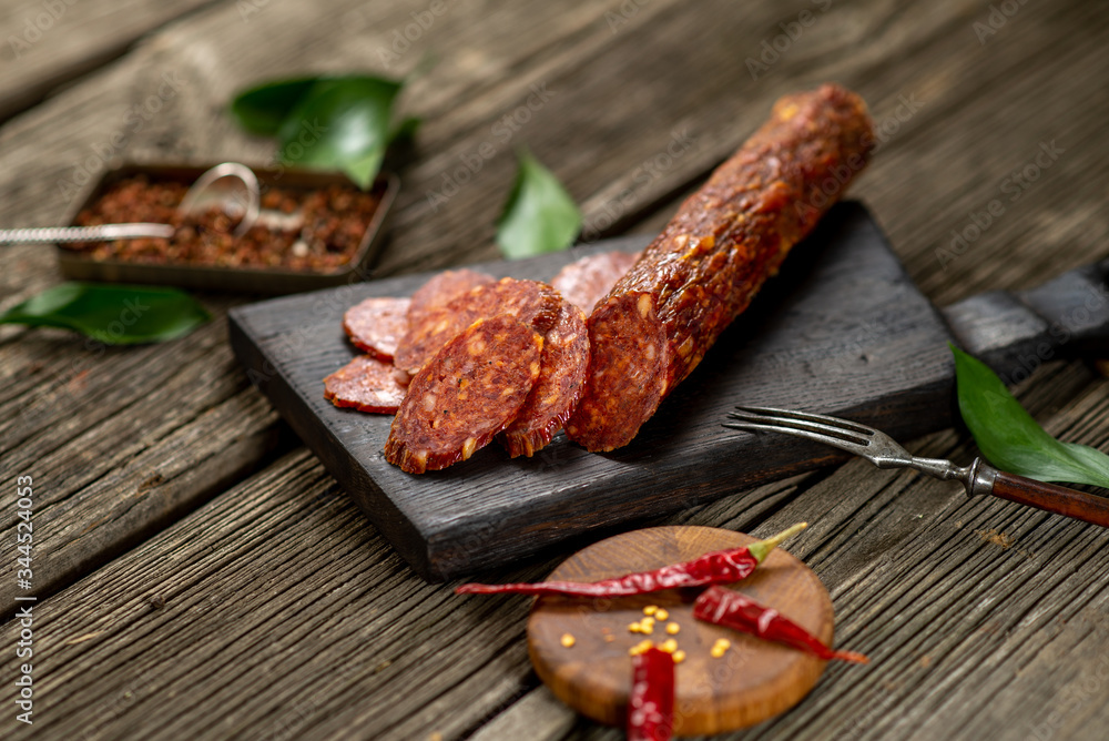 Dried sausage on wooden board with spices chili pepper wooden texture cuisine