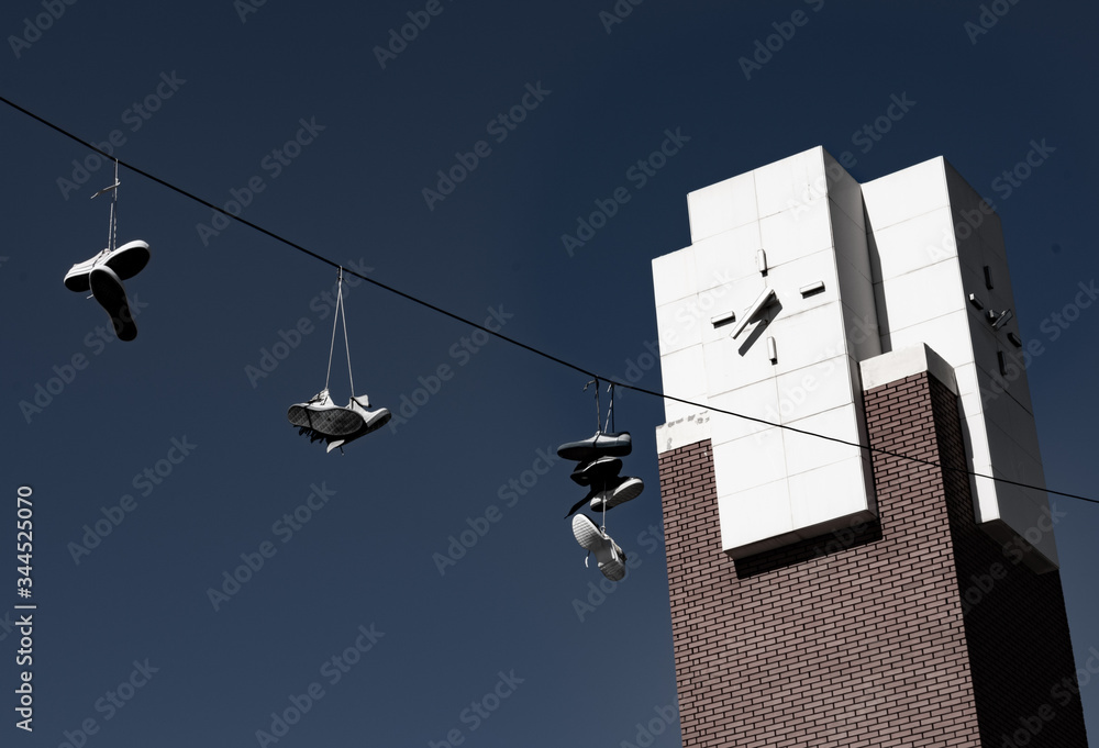 Obraz premium sneakers hanging on cables in working class neighborhood with clock tower