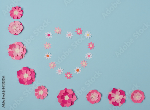 Paper flowers on a blue background. Concept Hello spring or summer template for design, greeting card, invitation, postcard Flatley top view copy space.