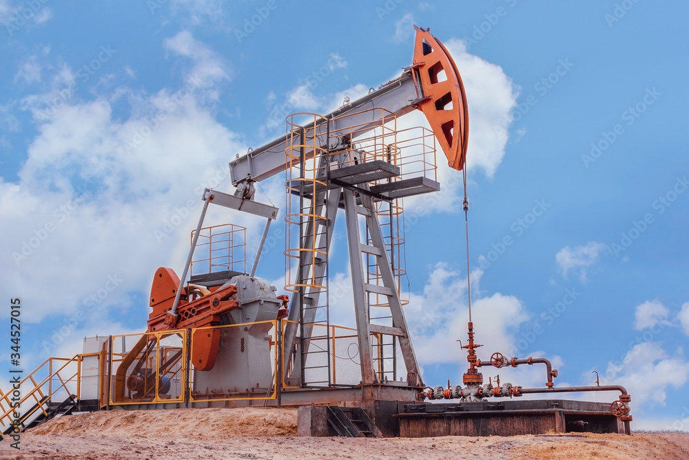 oil derrick pumps oil into a well against a blue sky background oil derrick pumps oil into a well against a blue sky background
