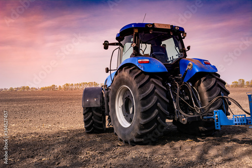 tractor in a field at sunset processes the field