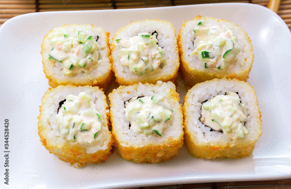 tempura Maki sushi rolls with cream cheese, on a white plate close-up. Deep-fried crab meat roll