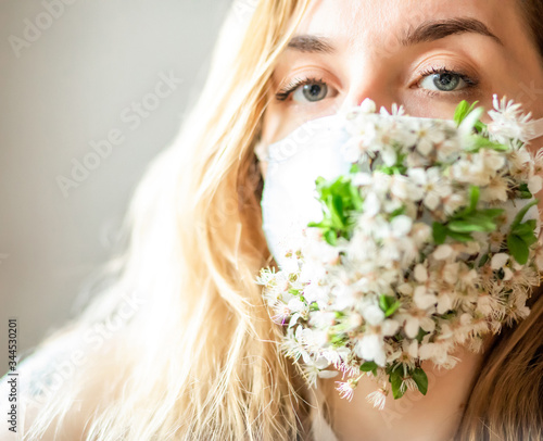 
girl in white medical mask and spring blossom