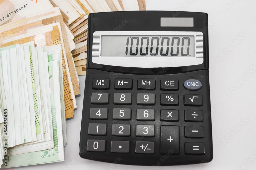 Million on the scoreboard of a calculator and a lot of euro banknotes on white. View from above. Close-up. Million on the scoreboard of a calculator and a lot of euro banknotes on white. View from above. Close-up.