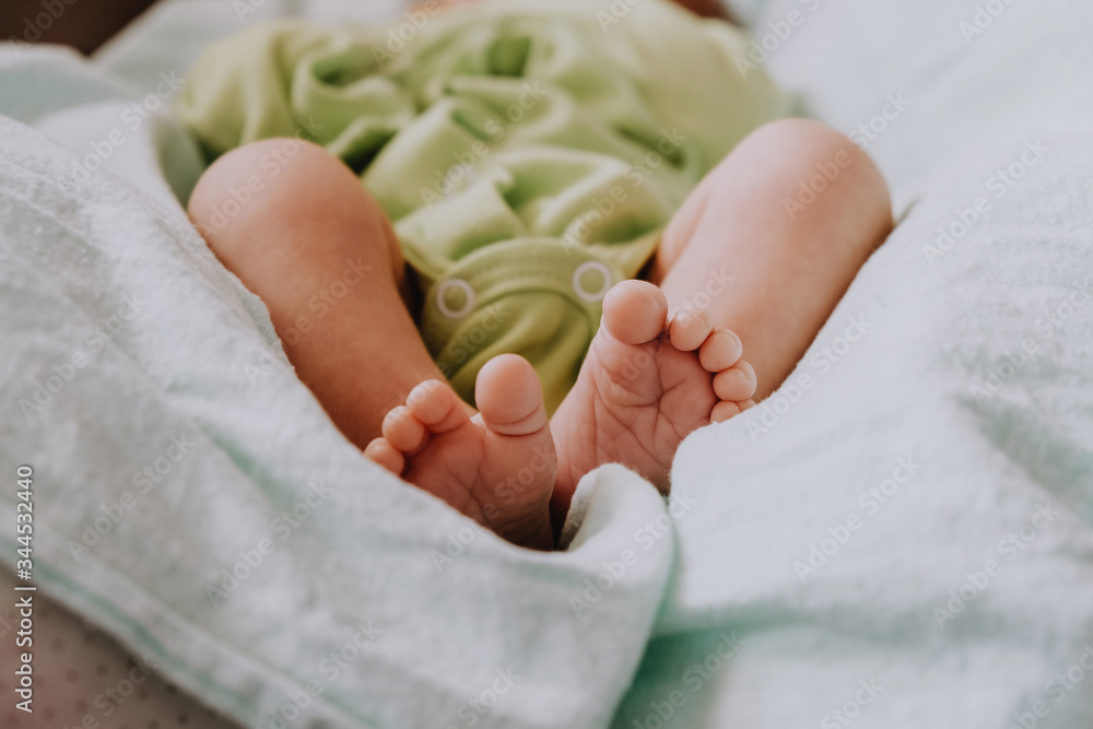 Tiny foots of newborn baby. Body of baby lying on back in bed. Tiny foots of newborn baby. Body of baby lying on back in bed.