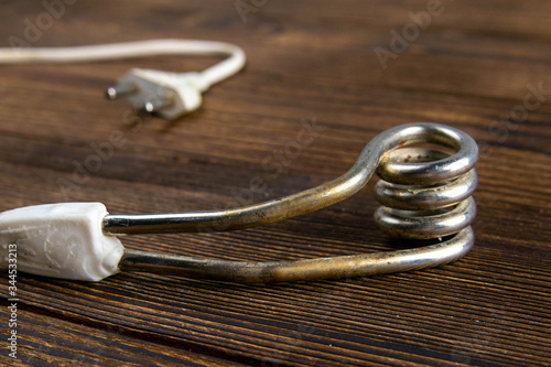 Old immersion water heater on dark wooden background. Close-up