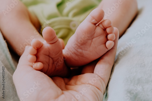 Little feet of newborn baby in mother's hand. Baby birth, maternity concept.