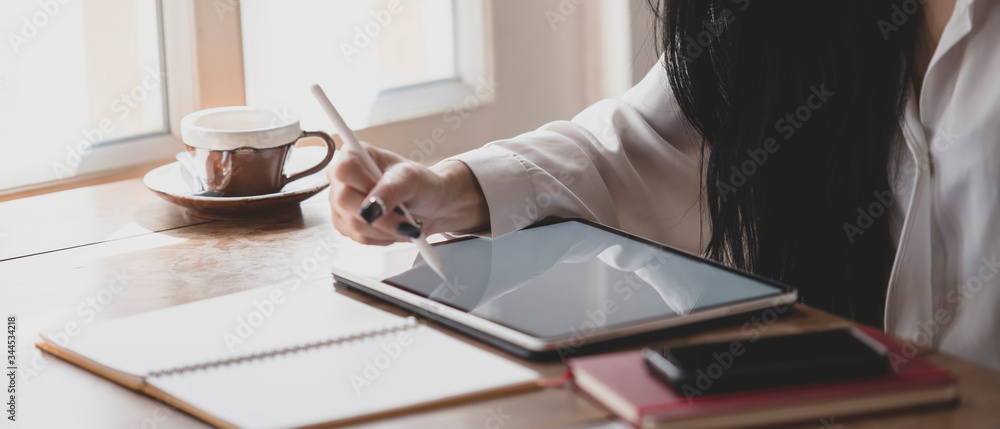 Woman at work reading and writing with tablet on the desk.