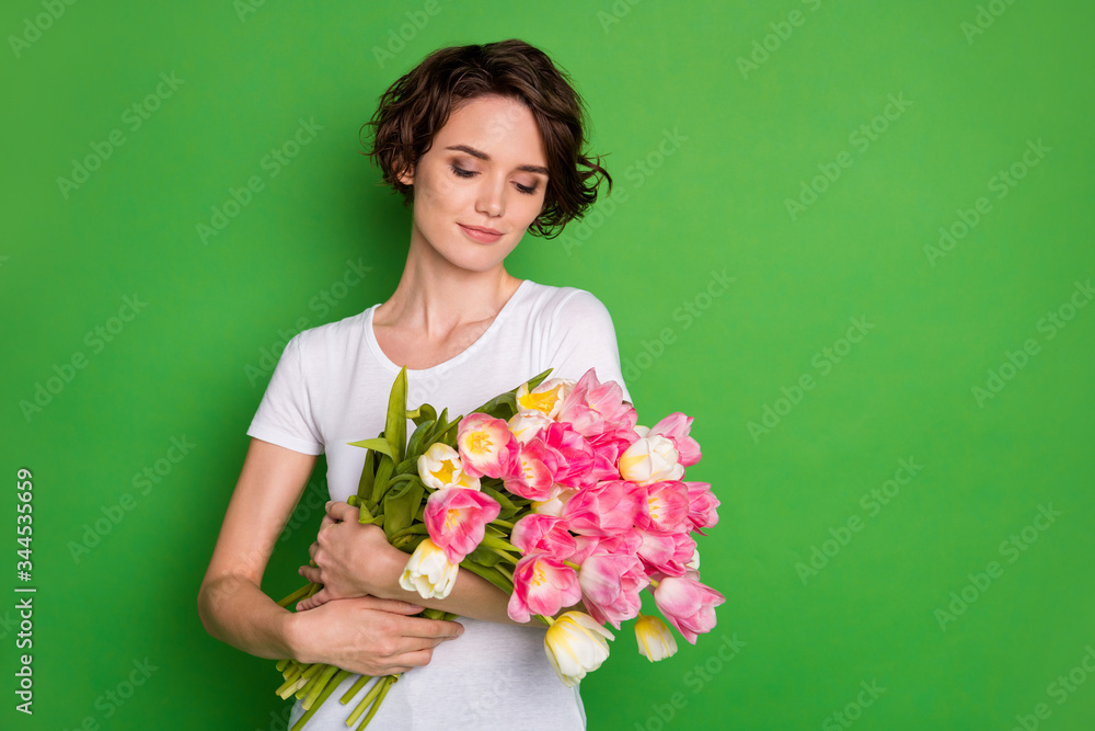 Photo of beautiful cute lady wavy short hairdo hold large big tulips surprise bunch present secret admirer delivery service wear casual white t-shirt isolated green color background Photo of beautiful cute lady wavy short hairdo hold large big tulips surprise bunch present secret admirer delivery service wear casual white t-shirt isolated green color background