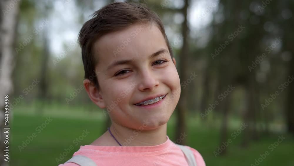 Portrait of cheerful boy in brackets outdoors. Cute guy smiling in garden. Portrait of cheerful boy in brackets outdoors. Cute guy smiling in garden.