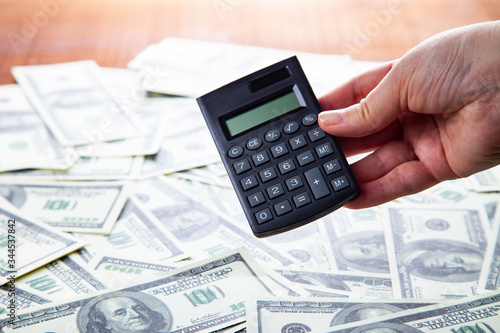 Calculator in hand on a background of dollars.