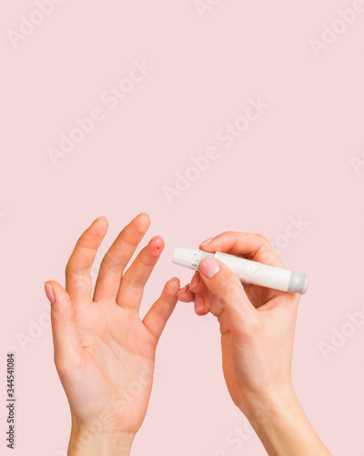 Close-up hands and lancet for glucose blood sample photo