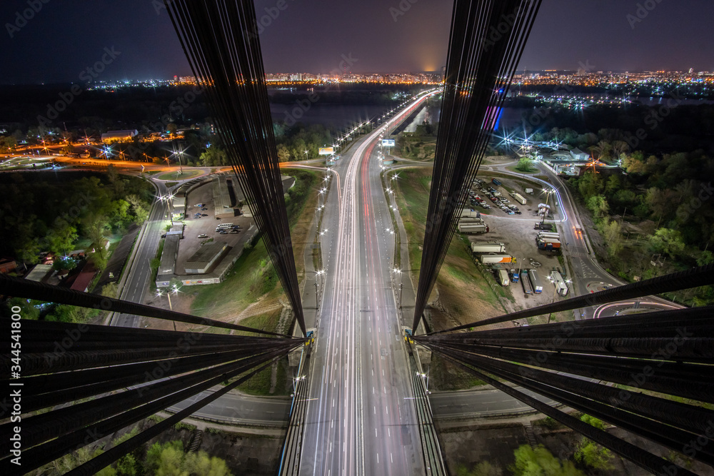 Fototapeta premium Aerial view of the bridge with the highway at night from the pylon of the cable-stayed bridge. View inside cable-stayed bridge.