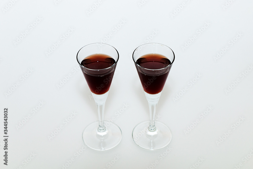 Two small glasses with red wine on a white background Two small glasses with red wine on a white background