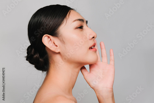 Beautiful asian woman  young asian girl with clean and bright skin  Cosmetic Beauty Concept hands touch on the cheek smily and friendly face isolated on grey background