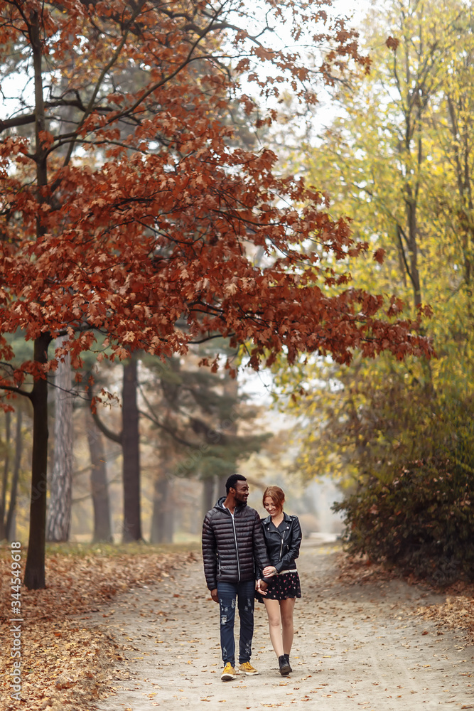 Happy interracial couple walking in autumn park