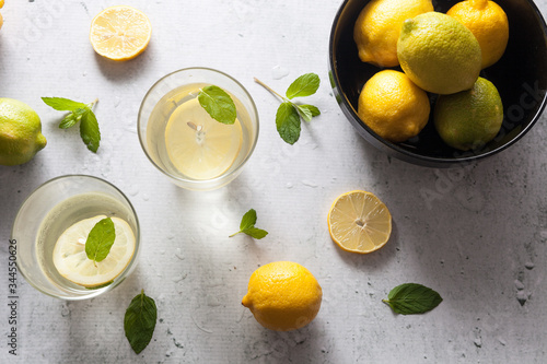 Glasses of water lamonade with lemon slices and fresh mint leaves green and yellow lemon on concrete background stone. Copy space. Flatlay, top view.