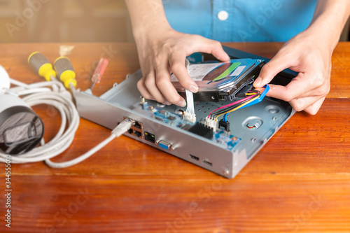 Technician remove a hard disk drive from the CCTV DVR recorder case , to install a new hard drive and upgrading to a Solid State Drive (SSD) in to surveillance DVR.