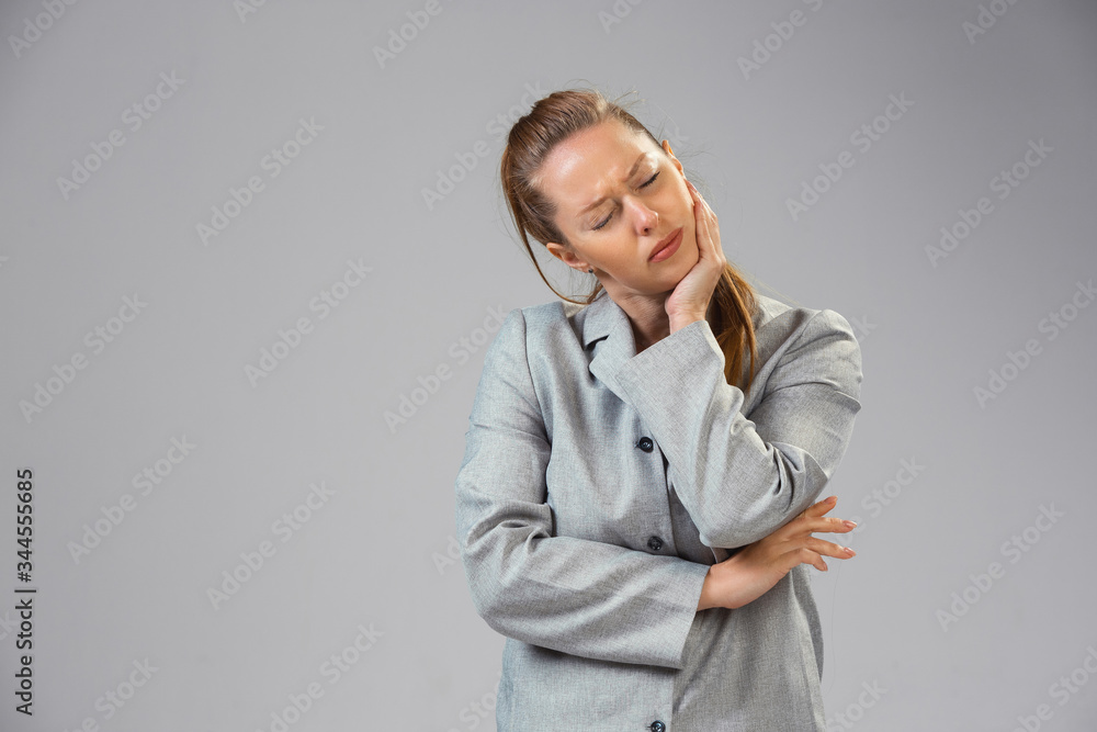 Young caucasian woman suffers from toothache, feels sick, ill and weakness isolted on gray studio background. Symptoms of desease or unhealthy lifestyle. Sickness, ilness, sad and upset. Copyspace. Young caucasian woman suffers from toothache, feels sick, ill and weakness isolted on gray studio background. Symptoms of desease or unhealthy lifestyle. Sickness, ilness, sad and upset. Copyspace.