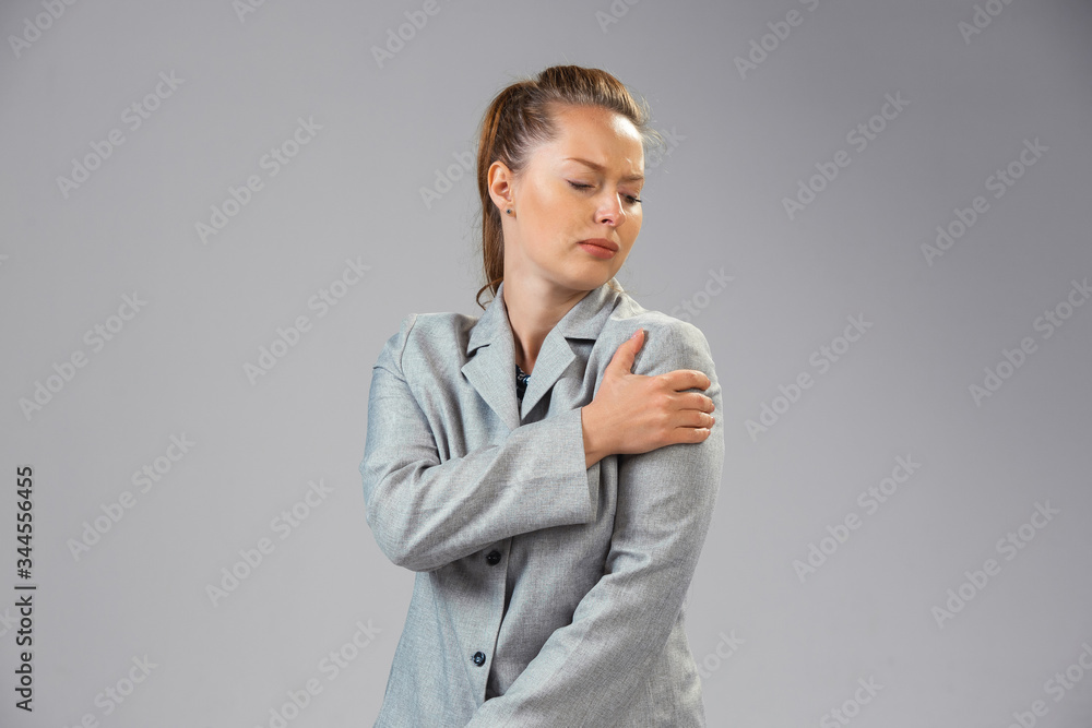Young caucasian woman suffers from shoulder pain, feels sick, ill and weakness isolted on gray studio background. Symptoms of desease or unhealthy lifestyle. Sickness, ilness, sad and upset. Copyspace Young caucasian woman suffers from shoulder pain, feels sick, ill and weakness isolted on gray studio background. Symptoms of desease or unhealthy lifestyle. Sickness, ilness, sad and upset. Copyspace