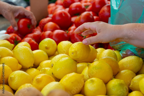 Woman select lemon and tomato on a street market in Greece. Sell local ecological fruits and vegetables  buy local food