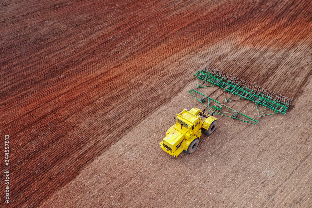 Spring agricultural work. Tractor plows red earth soil. Shooting from a drone. Spring agricultural work. Tractor plows red earth soil. Shooting from a drone.