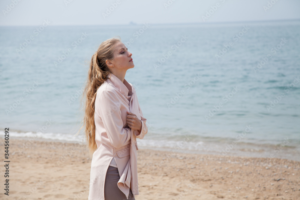 Beautiful blonde woman walks alone on a sandy beach by the sea Beautiful blonde woman walks alone on a sandy beach by the sea